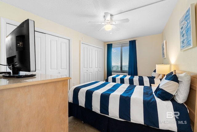 bedroom featuring light tile patterned floors, a ceiling fan, and multiple closets