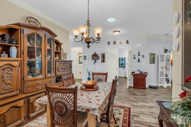 dining area with a notable chandelier, light wood-type flooring, and ornamental molding