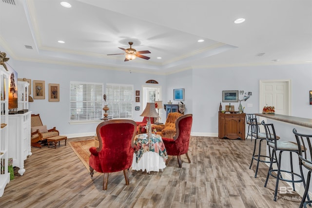 living room with a raised ceiling, ceiling fan, light hardwood / wood-style flooring, and ornamental molding