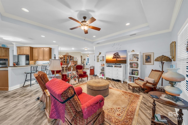 living room featuring ceiling fan, light hardwood / wood-style floors, crown molding, and a tray ceiling