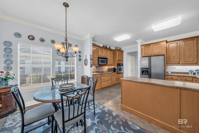 kitchen with pendant lighting, ornamental molding, appliances with stainless steel finishes, a notable chandelier, and light tile patterned flooring