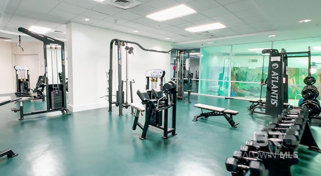 workout area featuring a drop ceiling, visible vents, and baseboards