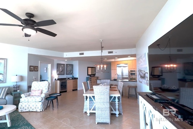 dining space with beverage cooler, ceiling fan with notable chandelier, visible vents, and light tile patterned flooring