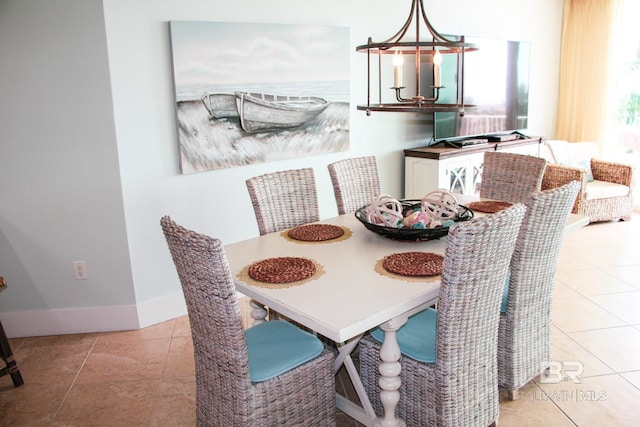 dining area featuring light tile patterned floors, baseboards, and an inviting chandelier