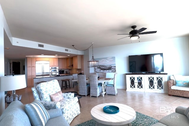 living room featuring light tile patterned floors, visible vents, and ceiling fan with notable chandelier