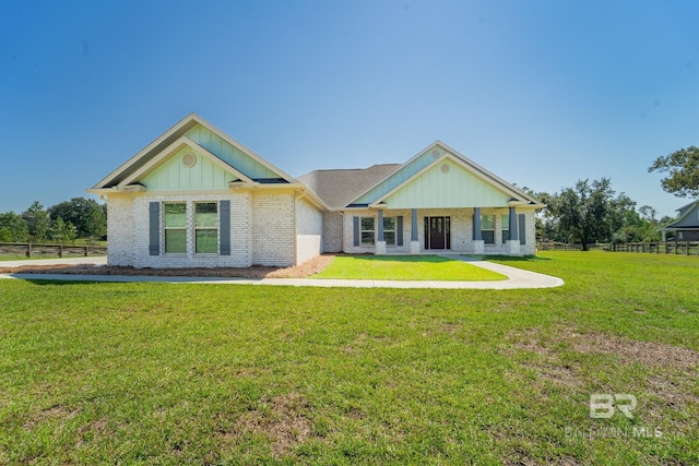 view of front of house featuring brick siding, a front lawn, board and batten siding, and fence
