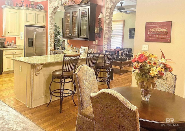 375 S Section St, Fairhope, AL 36532 - kitchen featuring ceiling fan, glass insert cabinets, light stone countertops, light wood-type flooring, and stainless steel refrigerator with ice dispenser