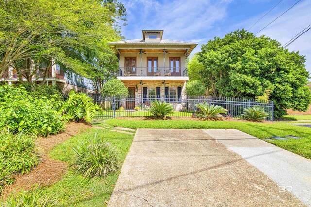 375 S Section St, Fairhope, AL 36532 - back of house with a fenced front yard, stone siding, a ceiling fan, and a balcony