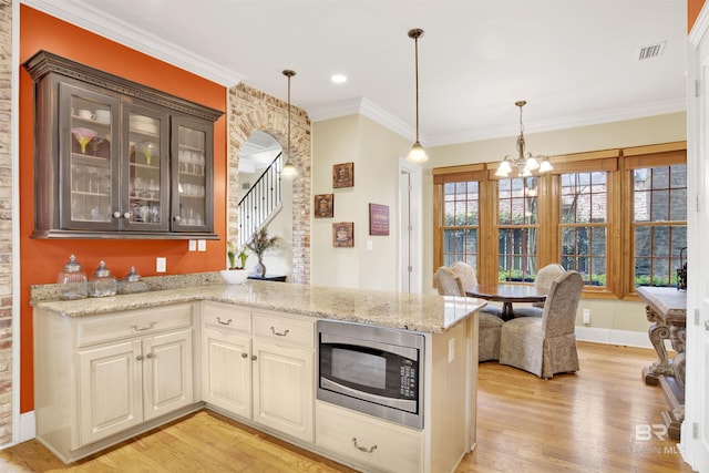 375 S Section St, Fairhope, AL 36532 - kitchen with stainless steel microwave, glass insert cabinets, light wood finished floors, and an inviting chandelier