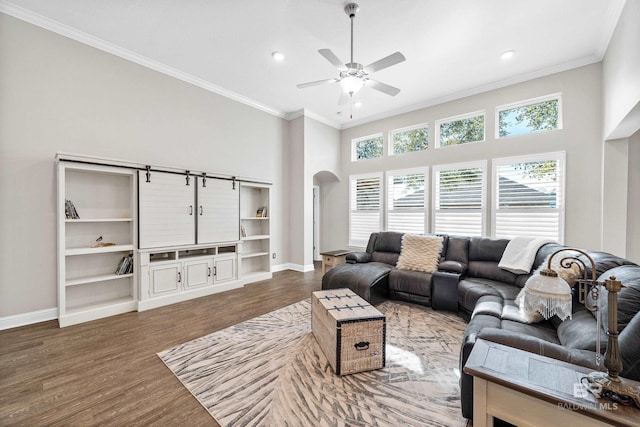 living room with ceiling fan, dark hardwood / wood-style flooring, ornamental molding, and a towering ceiling