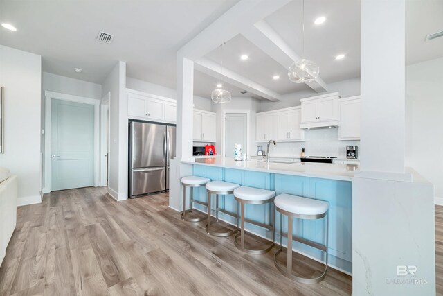3238 Sea Horse Cir, Gulf Shores, AL 36542 - kitchen featuring freestanding refrigerator, a breakfast bar, white cabinets, a sink, and light wood-style flooring