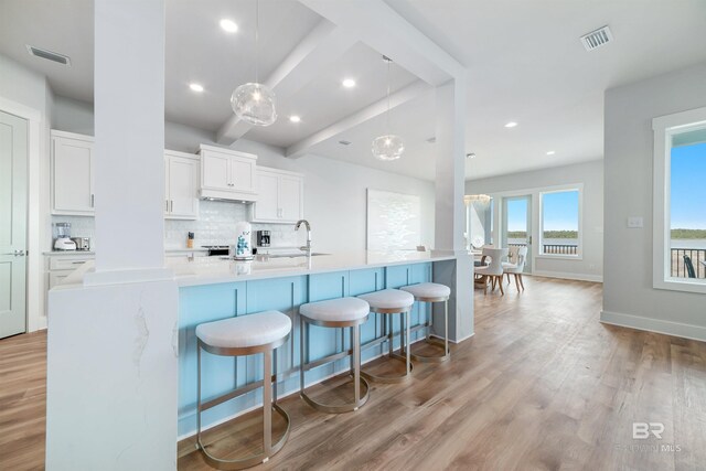 3238 Sea Horse Cir, Gulf Shores, AL 36542 - kitchen with backsplash, a kitchen bar, visible vents, white cabinets, and light wood-style flooring