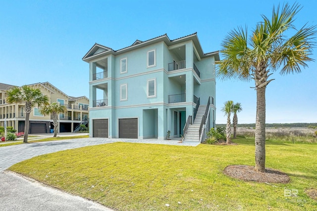 3238 Sea Horse Cir, Gulf Shores, AL 36542 - exterior space featuring a front yard, decorative driveway, stucco siding, an attached garage, and stairway