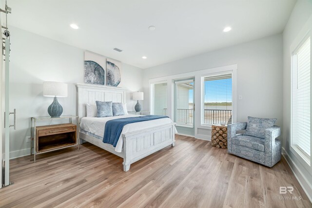 3238 Sea Horse Cir, Gulf Shores, AL 36542 - bedroom with visible vents, baseboards, light wood-type flooring, a barn door, and access to outside