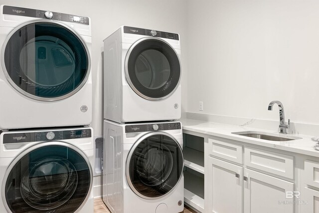 3238 Sea Horse Cir, Gulf Shores, AL 36542 - laundry room featuring cabinet space, light wood finished floors, a sink, and stacked washer and clothes dryer
