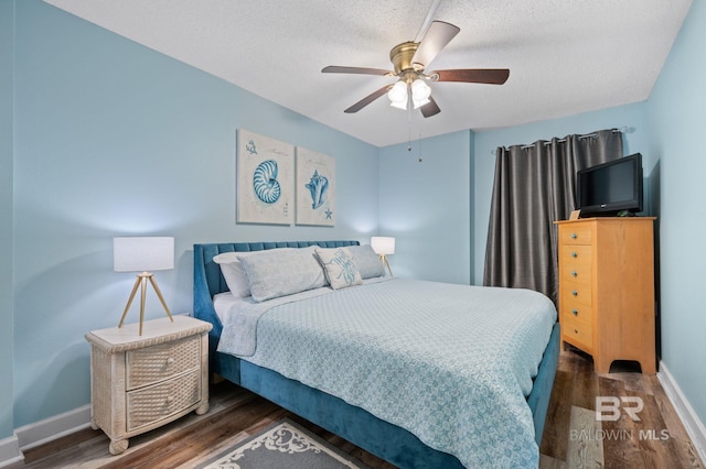 517 E Beach Blvd Unit 1B, Gulf Shores, AL 36542 - bedroom with wood finished floors, baseboards, a textured ceiling, and a ceiling fan