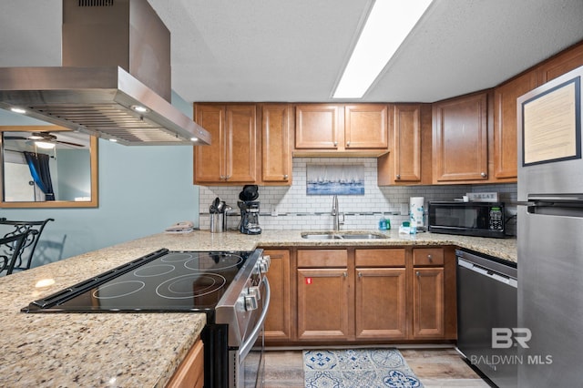517 E Beach Blvd Unit 1B, Gulf Shores, AL 36542 - kitchen with wall chimney range hood, a sink, stainless steel appliances, backsplash, and light wood finished floors