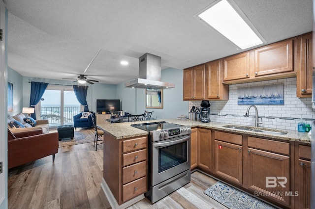 517 E Beach Blvd Unit 1B, Gulf Shores, AL 36542 - kitchen with stainless steel electric stove, a sink, island exhaust hood, a peninsula, and brown cabinetry