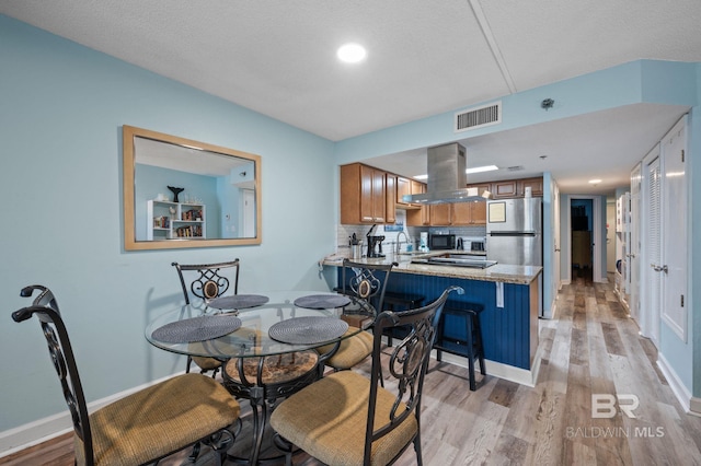 517 E Beach Blvd Unit 1B, Gulf Shores, AL 36542 - dining space with light wood-style floors, baseboards, and a textured ceiling
