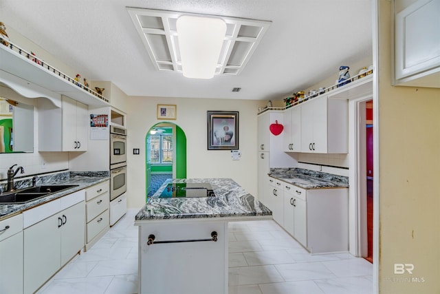 kitchen with a kitchen island, sink, and white cabinets