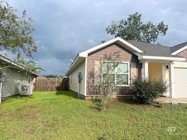 view of side of home with a yard, a garage, and central AC