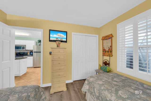 bedroom featuring light hardwood / wood-style flooring, stainless steel fridge, and a closet