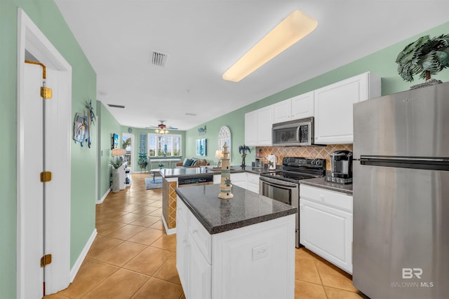 kitchen with appliances with stainless steel finishes, kitchen peninsula, white cabinets, and tasteful backsplash