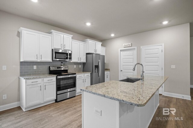 kitchen featuring backsplash, sink, light wood-type flooring, appliances with stainless steel finishes, and white cabinets