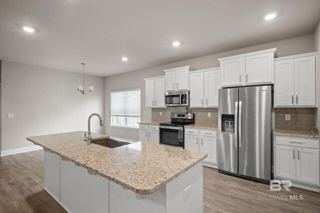 kitchen with tasteful backsplash, white cabinetry, appliances with stainless steel finishes, and light stone countertops