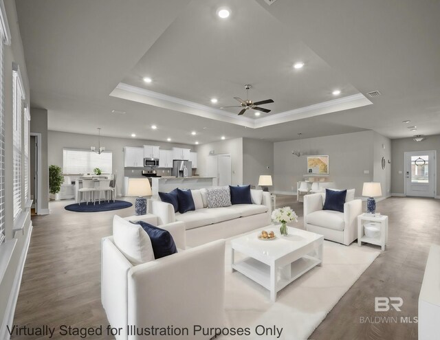 unfurnished living room with hardwood / wood-style flooring, ceiling fan with notable chandelier, and a tray ceiling