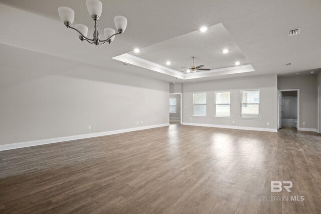 unfurnished living room featuring ceiling fan with notable chandelier, a raised ceiling, and light hardwood / wood-style floors