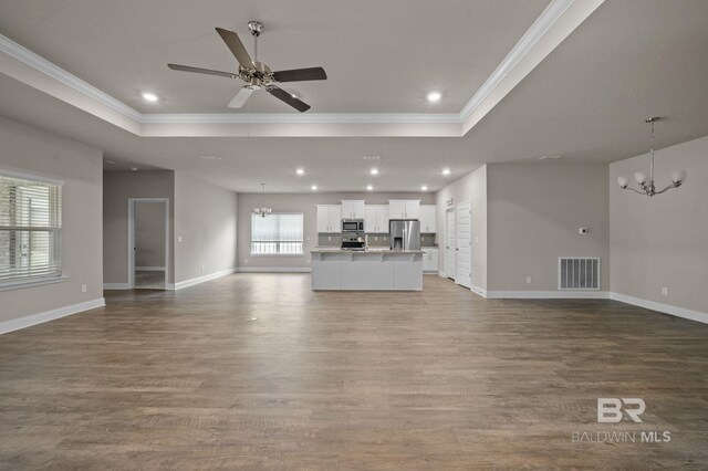 kitchen with light hardwood / wood-style floors, stainless steel dishwasher, ceiling fan with notable chandelier, white cabinets, and a tray ceiling