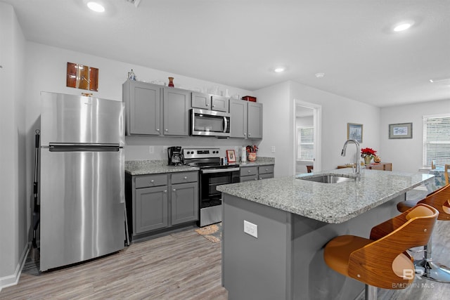 10804 Burlington Way, Mobile, AL 36608 - kitchen with appliances with stainless steel finishes, gray cabinets, light wood-style floors, a breakfast bar area, and light stone countertops