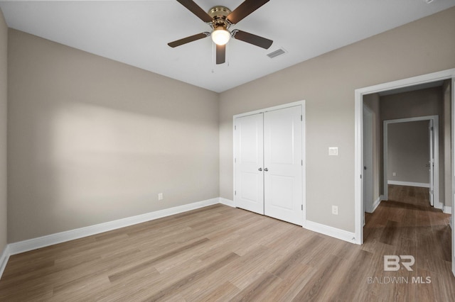 unfurnished bedroom with light wood-type flooring, ceiling fan, and a closet