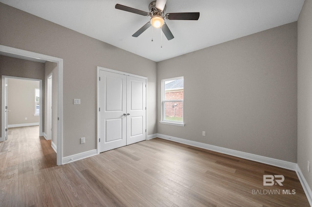 unfurnished bedroom featuring light hardwood / wood-style flooring, ceiling fan, and a closet