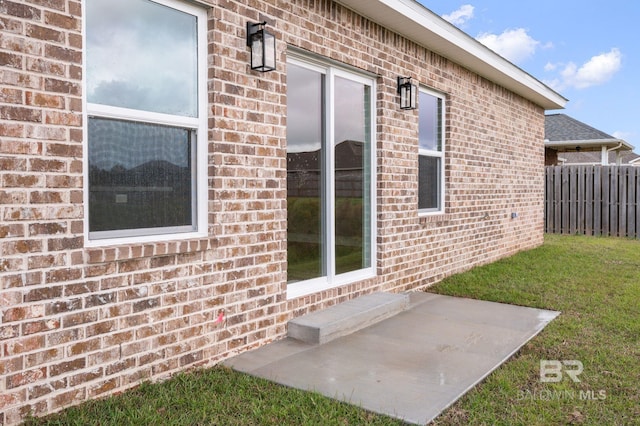 view of exterior entry with a patio area and a lawn