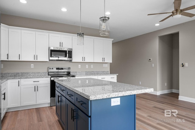 kitchen featuring light wood-type flooring, appliances with stainless steel finishes, a center island, and white cabinets