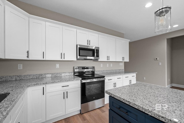 kitchen with light hardwood / wood-style floors, appliances with stainless steel finishes, light stone countertops, blue cabinets, and white cabinets