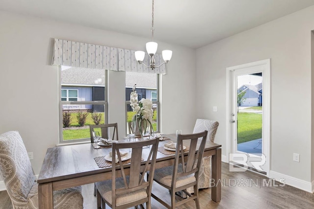 dining room featuring baseboards, plenty of natural light, an inviting chandelier, and wood finished floors