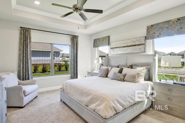 carpeted bedroom featuring crown molding, a tray ceiling, ceiling fan, and baseboards