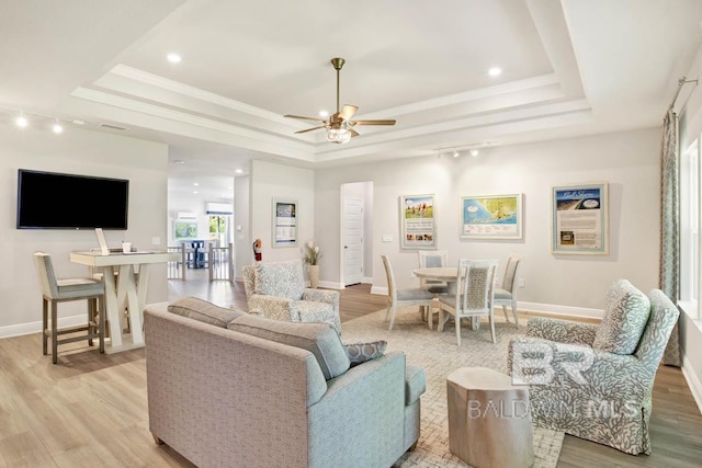 living room with light wood finished floors and a raised ceiling