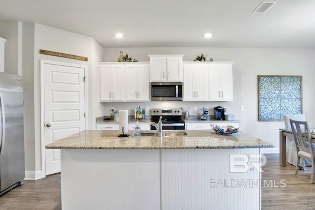 kitchen featuring light stone counters, visible vents, appliances with stainless steel finishes, white cabinetry, and wood finished floors