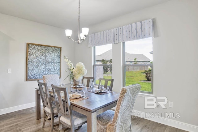 dining area with a chandelier, wood finished floors, and baseboards