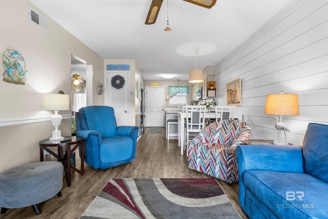 728 W Beach Blvd Unit 104, Gulf Shores, AL 36542 - living room featuring a ceiling fan, wood walls, wood finished floors, and visible vents