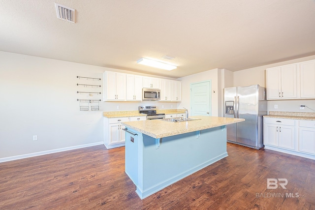 kitchen with a kitchen island with sink, a kitchen breakfast bar, sink, white cabinetry, and stainless steel appliances