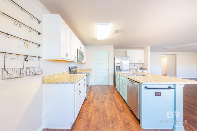 kitchen with a kitchen island with sink, dark wood-type flooring, sink, white cabinetry, and stainless steel appliances