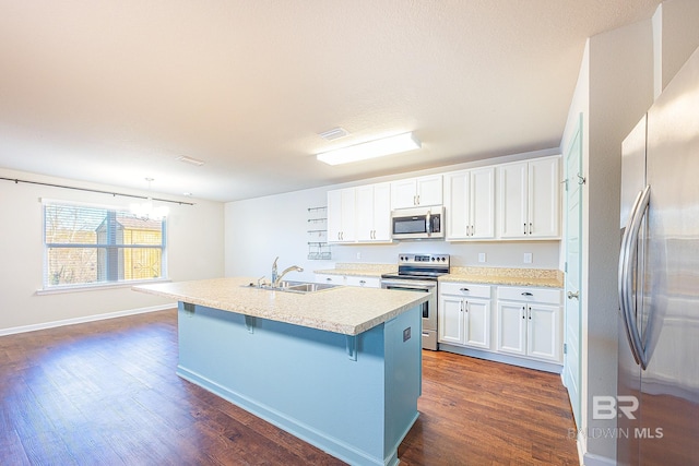 kitchen featuring an island with sink, pendant lighting, a breakfast bar area, white cabinets, and appliances with stainless steel finishes