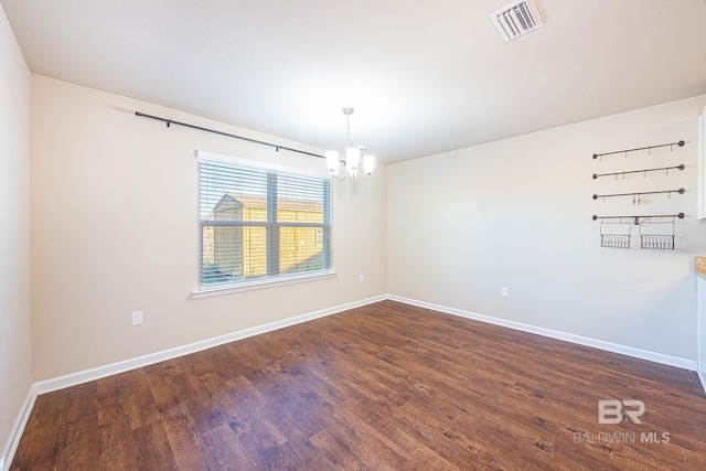 empty room featuring dark hardwood / wood-style flooring and a notable chandelier