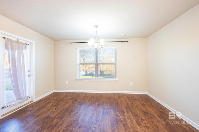 empty room with a chandelier and dark hardwood / wood-style flooring