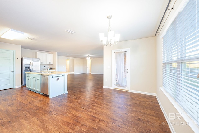 kitchen featuring pendant lighting, an inviting chandelier, a center island with sink, appliances with stainless steel finishes, and white cabinetry